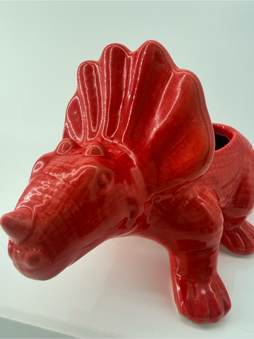 Vibrant red ceramic Triceratops dinosaur planter.